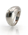 Handcrafted sterling silver statement ring with organic, hammered texture and curved dome design, reflecting light for a bold, contemporary look