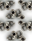 Metallic silver drop-shaped ornaments with hollow centers arranged in a symmetrical pattern on a white background, showcasing their versatile design for jewelry making.