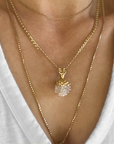 Cherry Pine pendant necklace featuring gold-plated top and clear resin bottom, resembling a pinecone, worn on layered gold chains against a white background, showcasing its unique nature-inspired design and delicate craftsmanship.