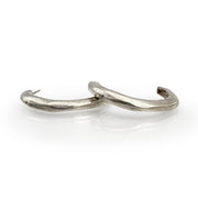 Elegant silver J-hoop earrings with a sleek, curved design, showcasing a minimalist yet sophisticated style perfect for everyday wear or special occasions